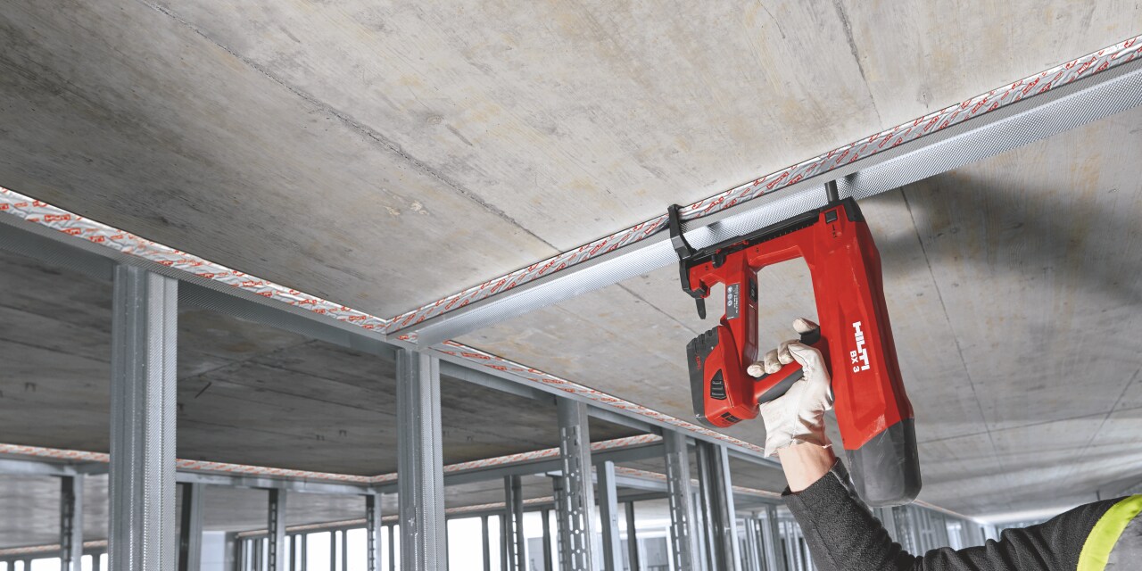 Photo of CFS-TTS Top track seal being installed on top of drywall track and filling the gap between the metal frame and the concrete ceiling.