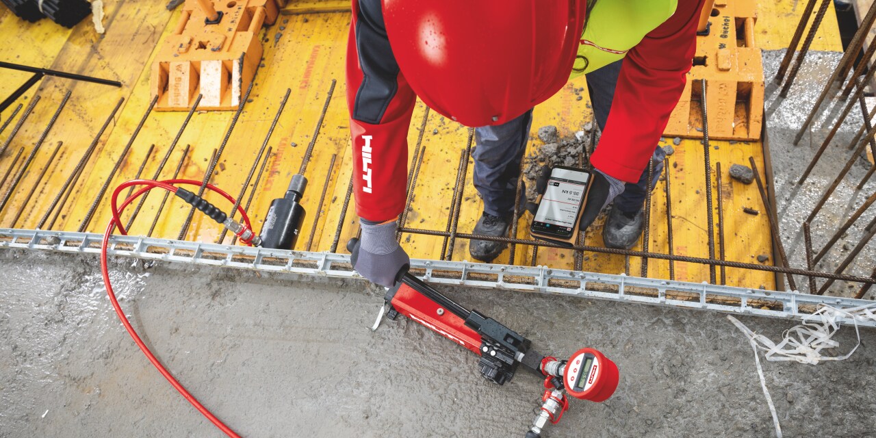 On-site anchor testing equipment with wireless data transfer to a smartphone being used in a concrete floor slab