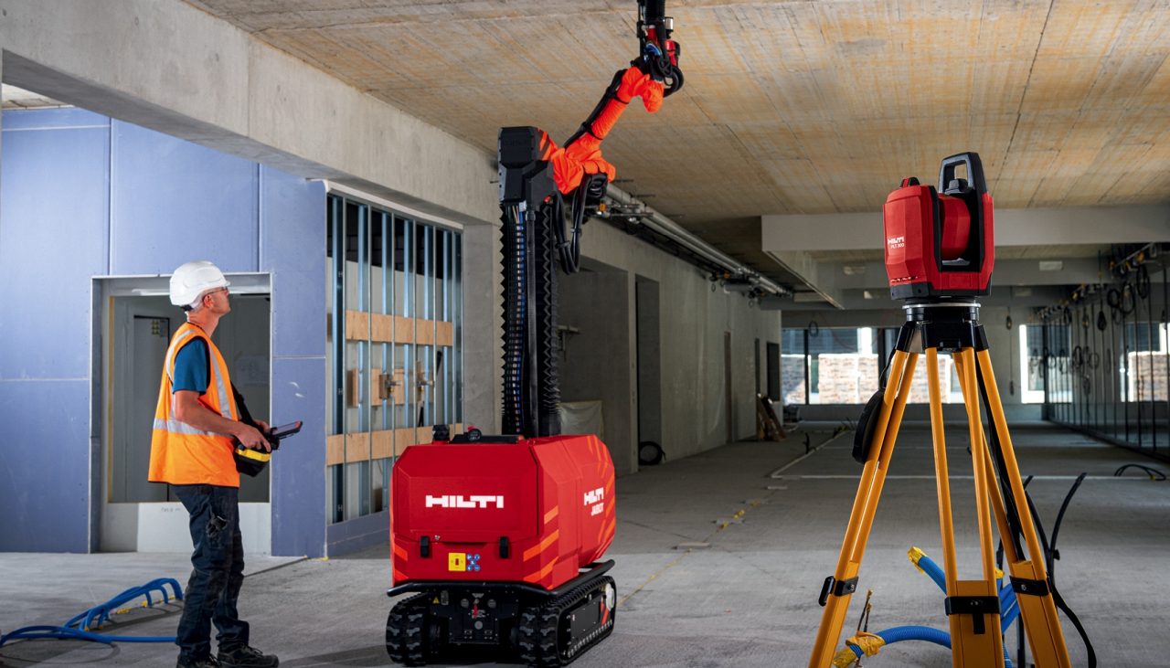 Construction worker safely operating ceiling drilling robot Jaibot on a jobsite