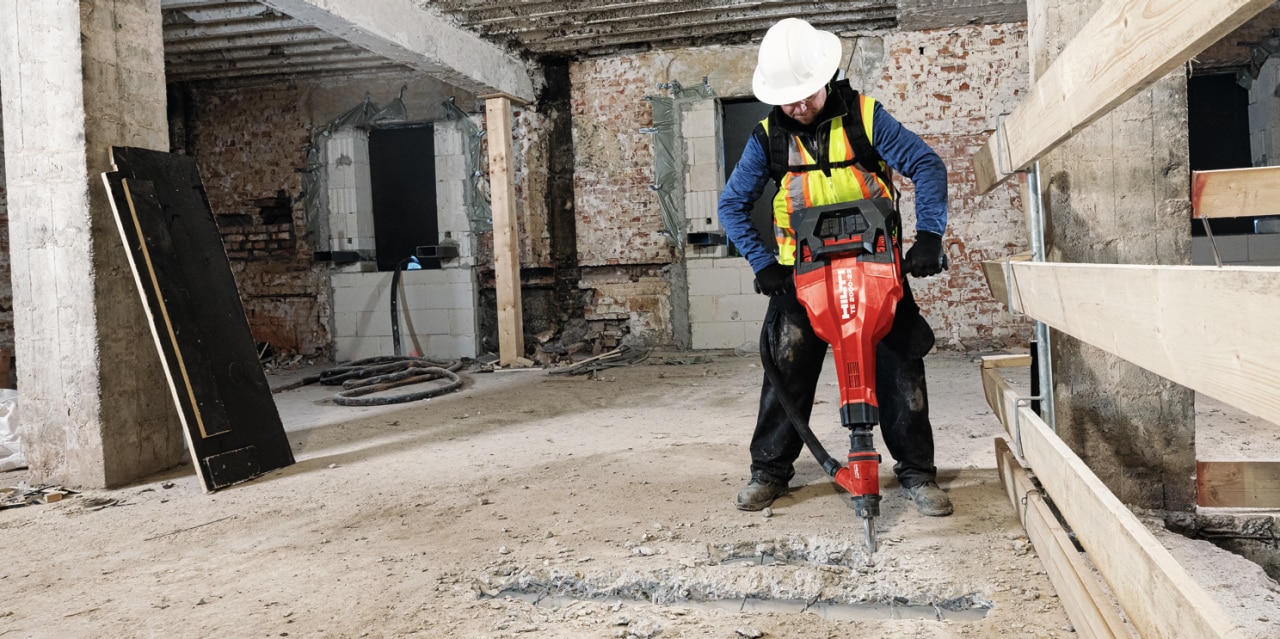 Hilti battery on cordless tool, gloved hand moves the tool's dial