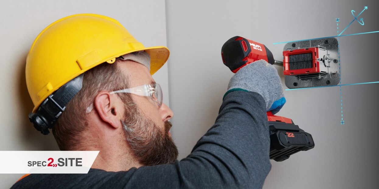 a worker uses a cordless driver to install a firestop device to a wall