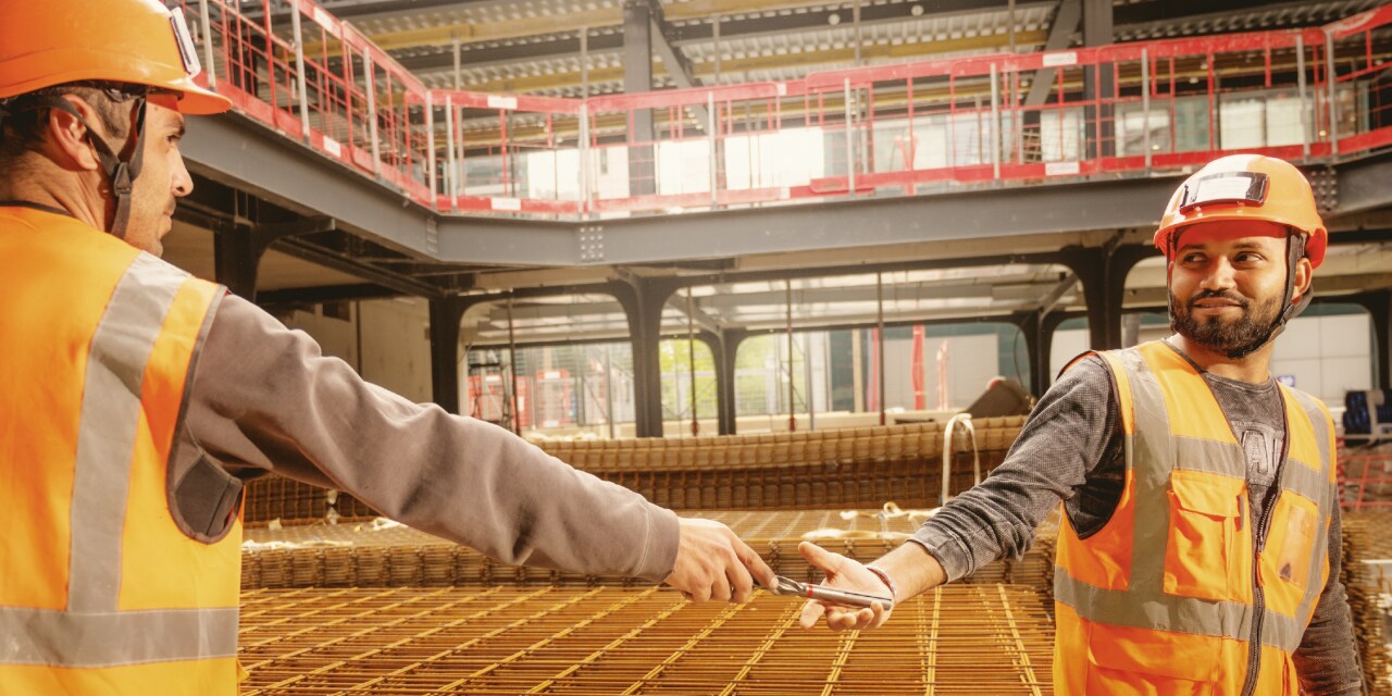 two workers passing drill bits to each other