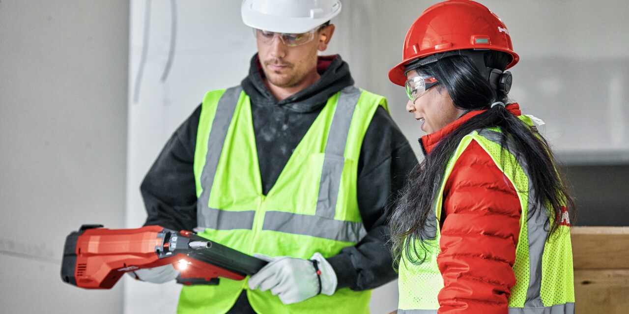 Man and a woman discussing Hilti BX4 power tool on construction site.
