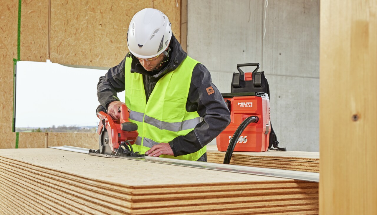 Construction worker using Hilti tool connected to a vaccuum cleaner
