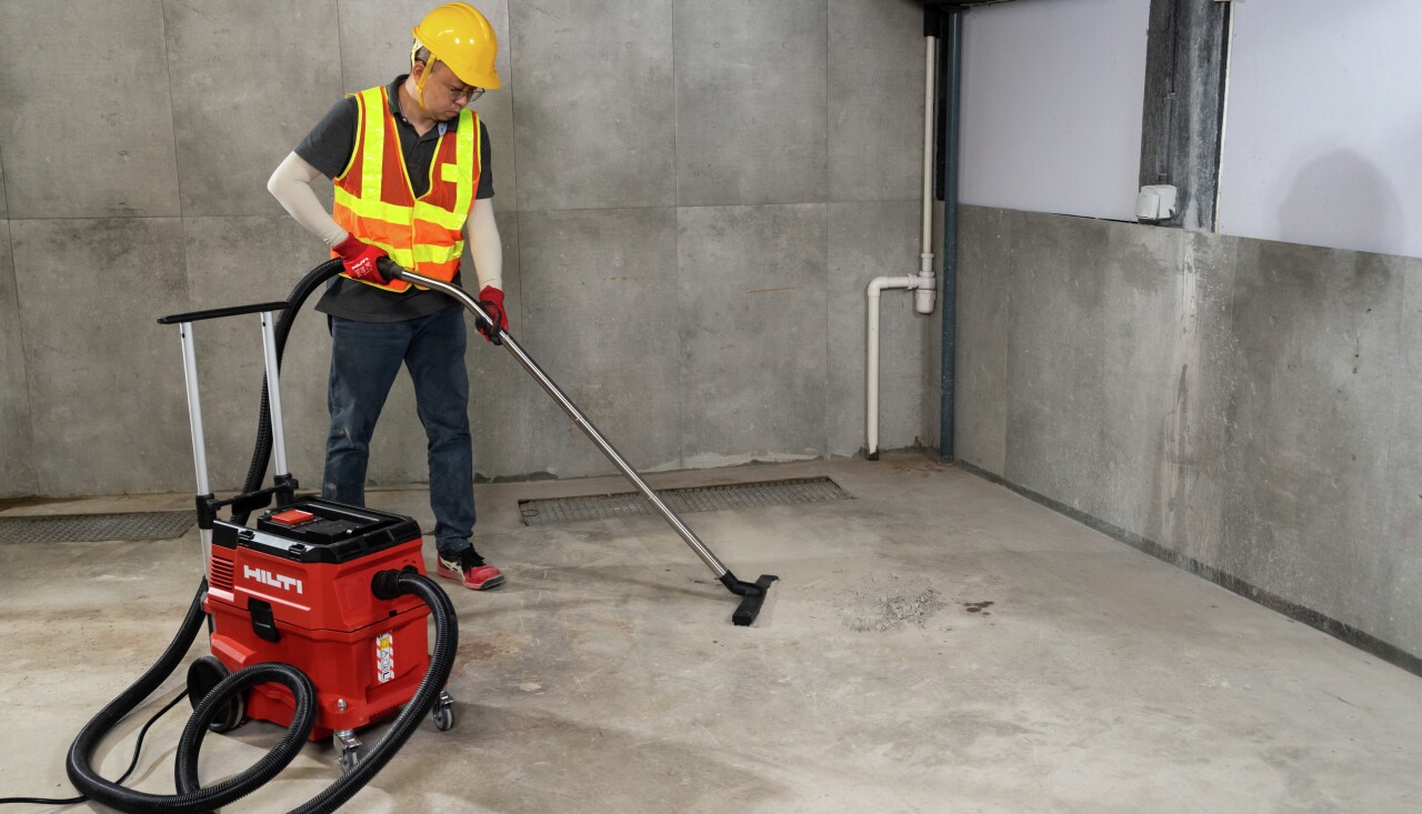 Construction worker using Hilti tool connected to a vaccuum cleaner
