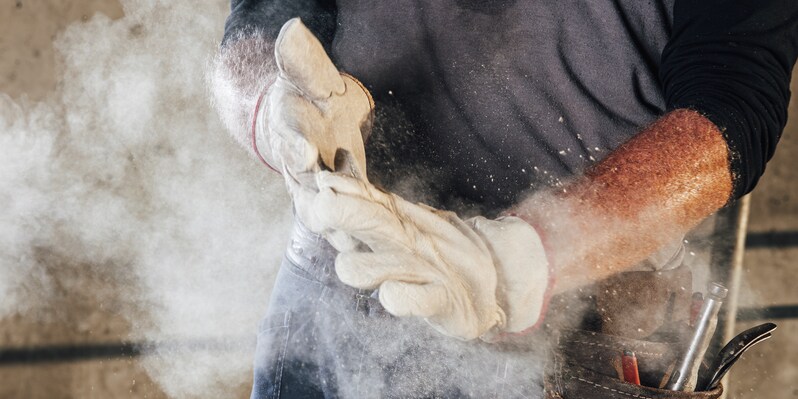 construction worker rubbing his gloves trying to get rid of dust