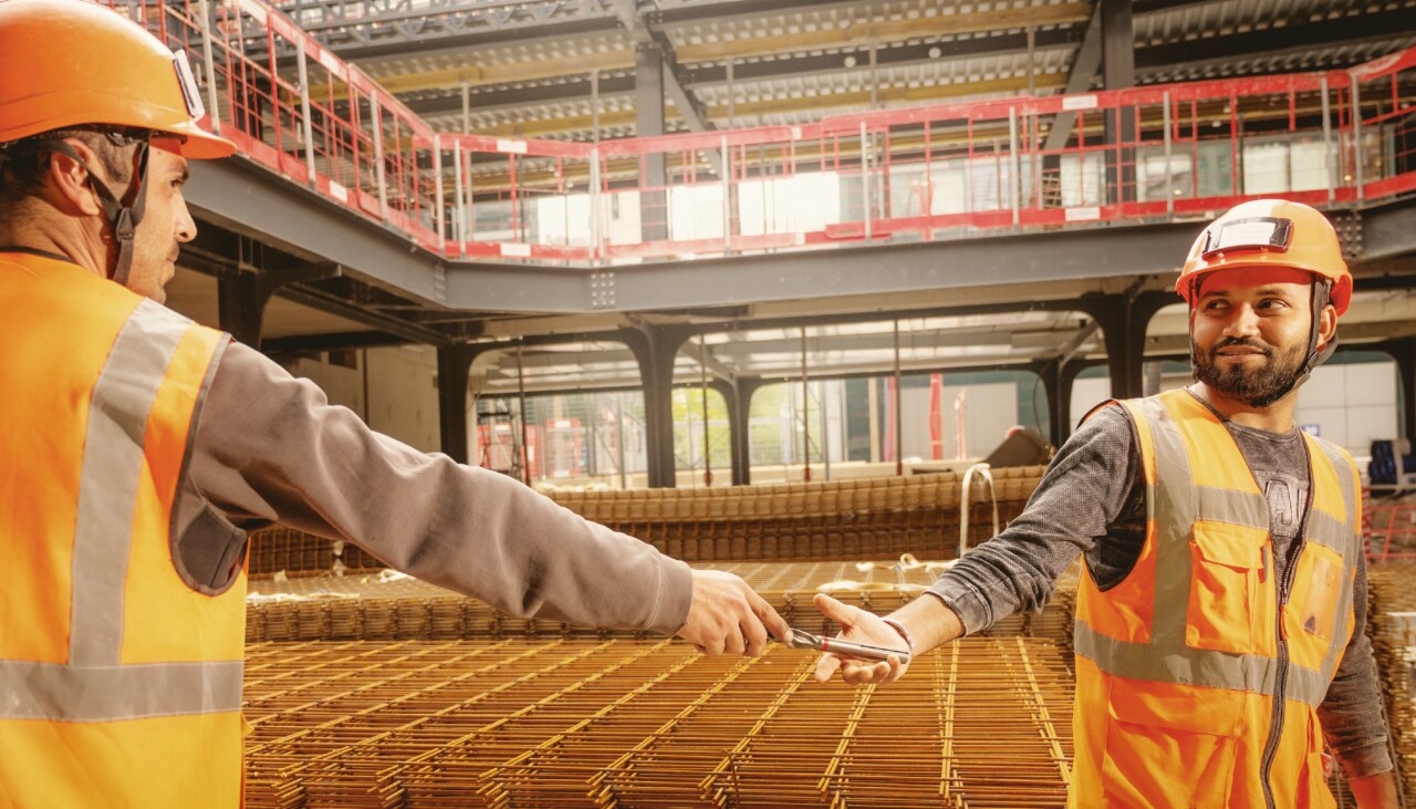 jobiste worker sharing drill bit with his colleague