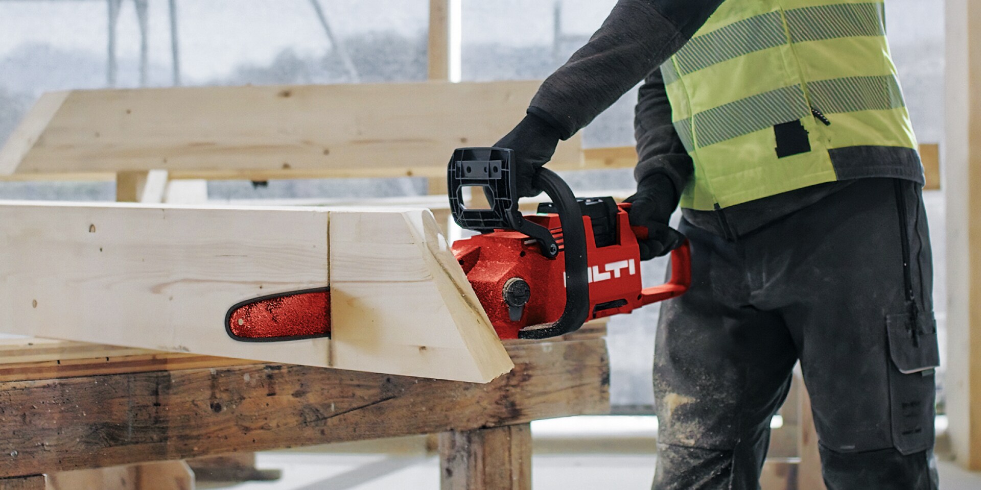 Un ouvrier coupe un morceau de bois avec une tronçonneuse sans fil
