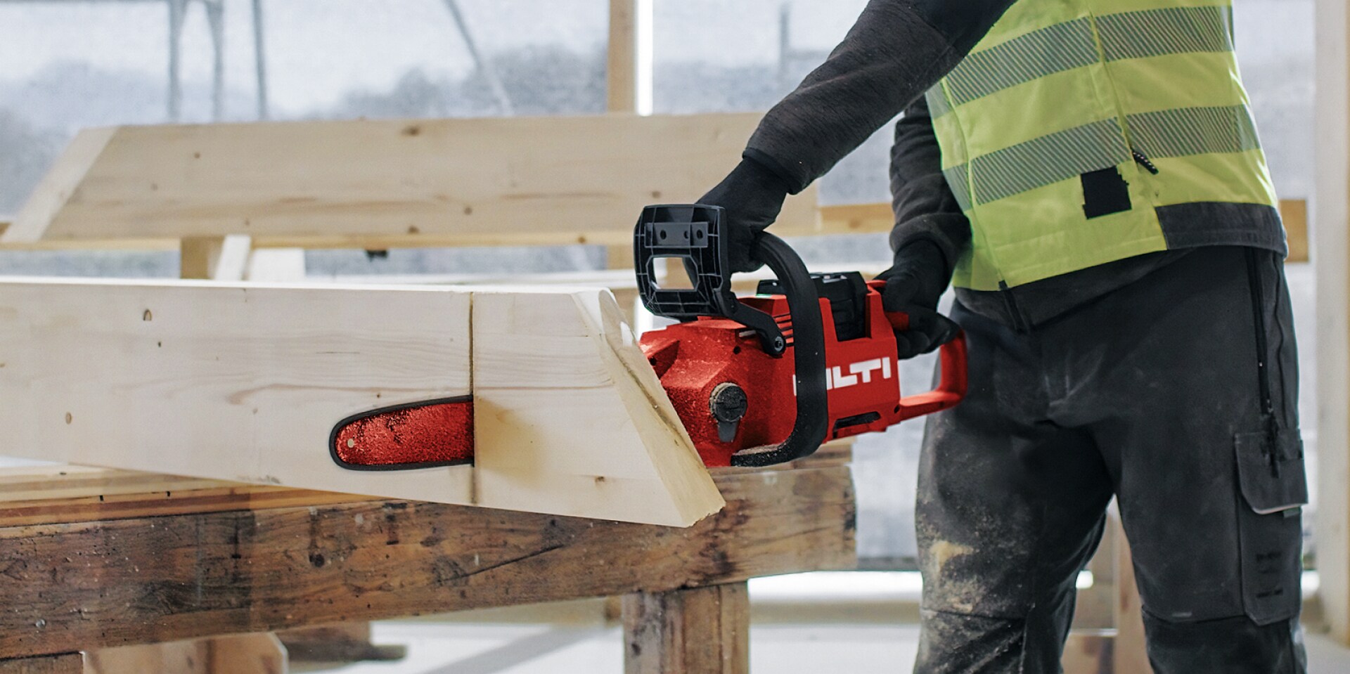 Werknemer snijdt een blok hout met de snoerloze kettingzaag