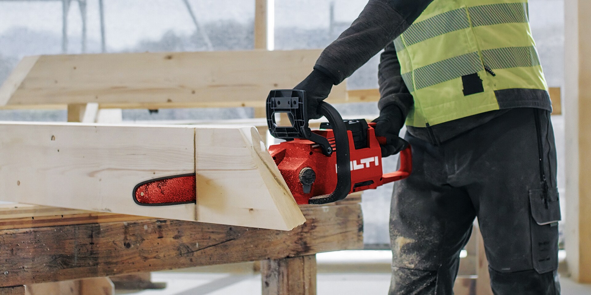 Un ouvrier coupe un morceau de bois avec une tronçonneuse sans fil.