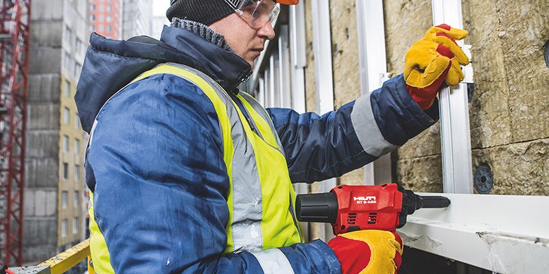 Pracownik łączy śrubami podkonstrukcję fasady