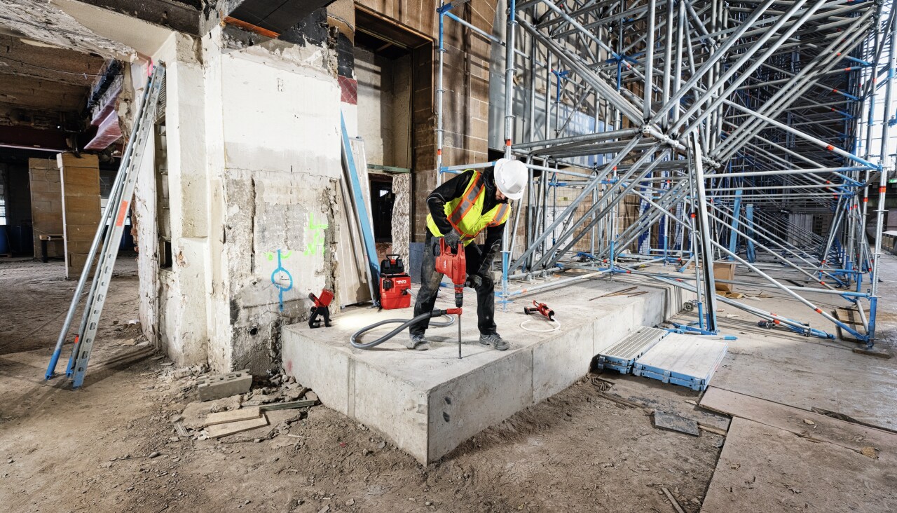 Професионалист, пробиващ отвори в бетонен блок с помощта на ударно-пробивна машина TE 60-22 и прахосмукачка VC 10-22