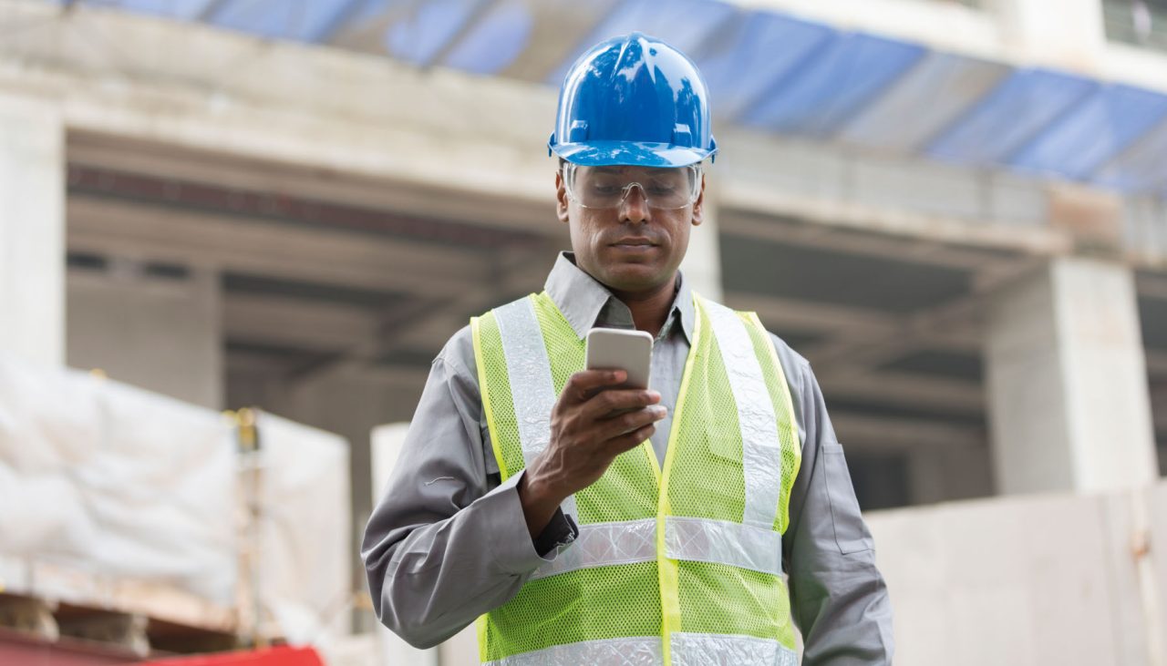 Portrait of a male Indian builder or industrial engineer at work using phone.