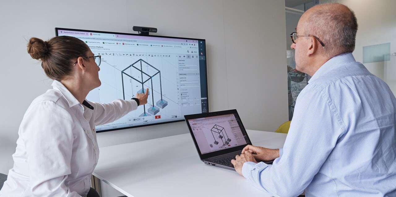 „Hilti“ inžinierius, dirbantis vietoje su klientu, o pirmame plane - parduotuvės brėžiniai