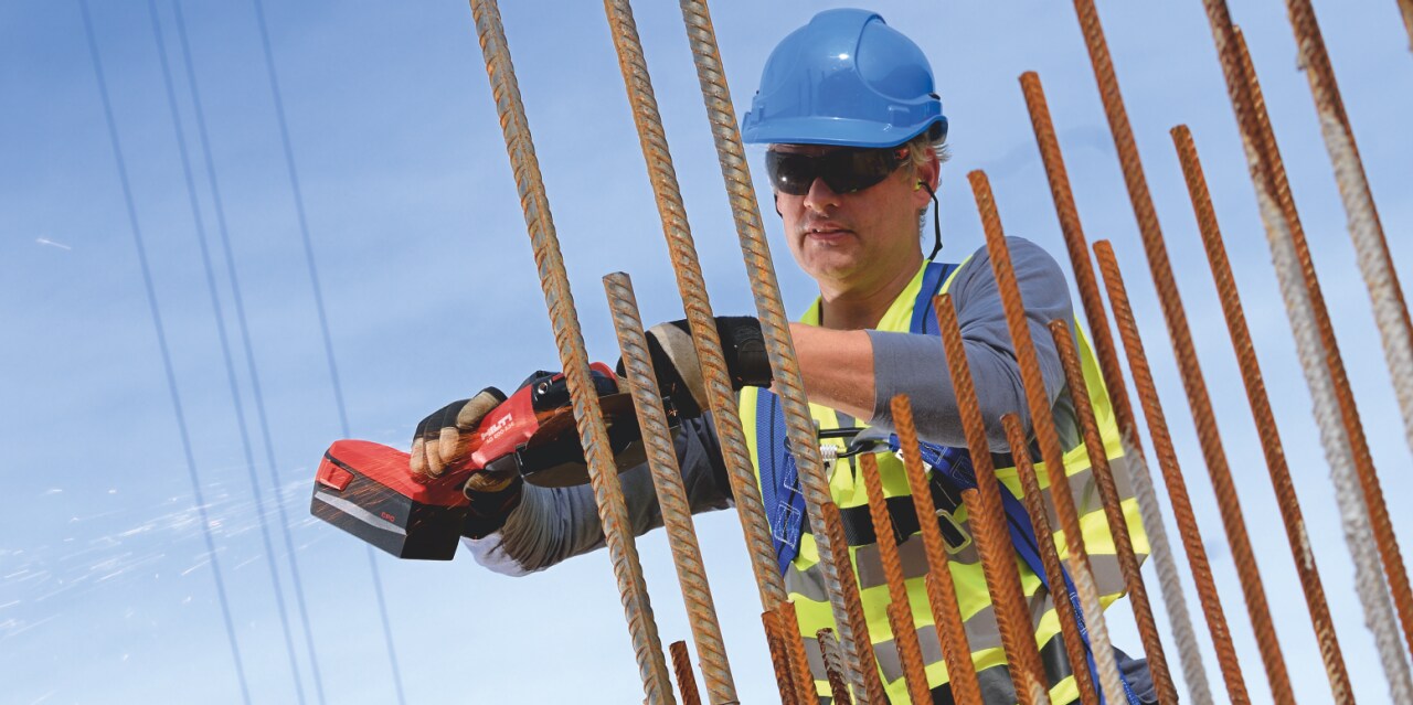 Construction worker cutting rebar using a AG 600-A36 Cordless angle grinder with Active Torque Control (ATC) to help prevent kickback