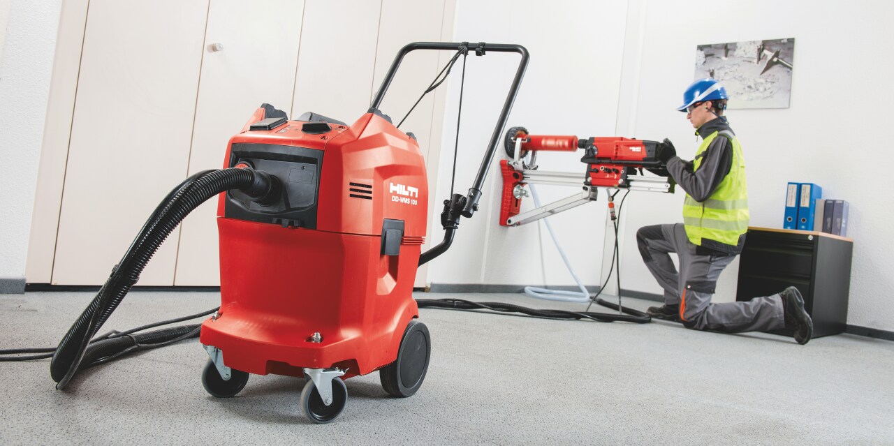 Construction worker using a DD-WMS water management system to supply, filter and collect slurry from wet diamond drilling