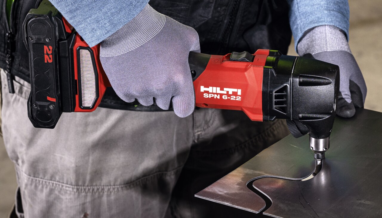 Hombre usando una cortadora inalámbrica en metal